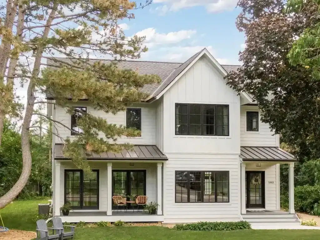 Contemporary white house with large windows, front porch, and surrounding greenery, showcasing resid.