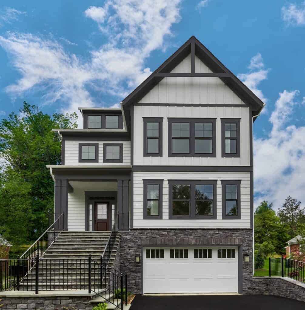 Contemporary house with black and white siding and large windows.