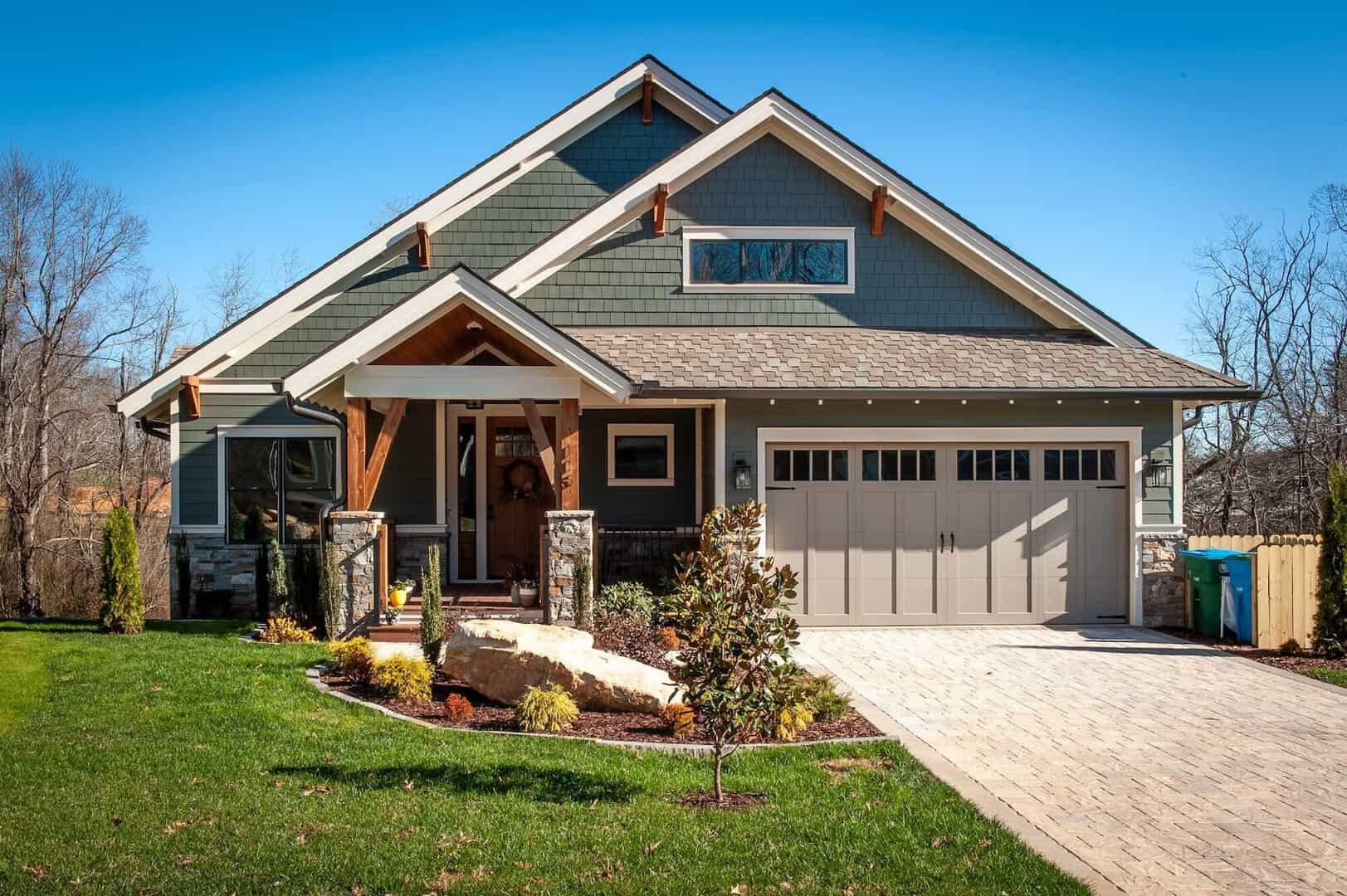 Contemporary house with new siding, front yard, and garage under clear blue sky.
